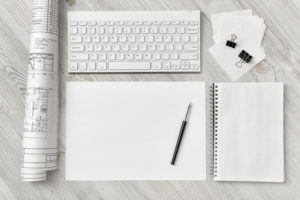 Blank piece of paper and notebook on desk
