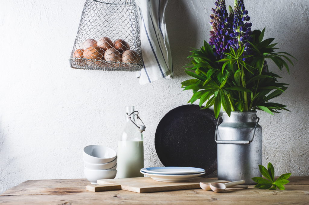 Lupines in a can, milk, eggs and ware on a wooden table against a white wall