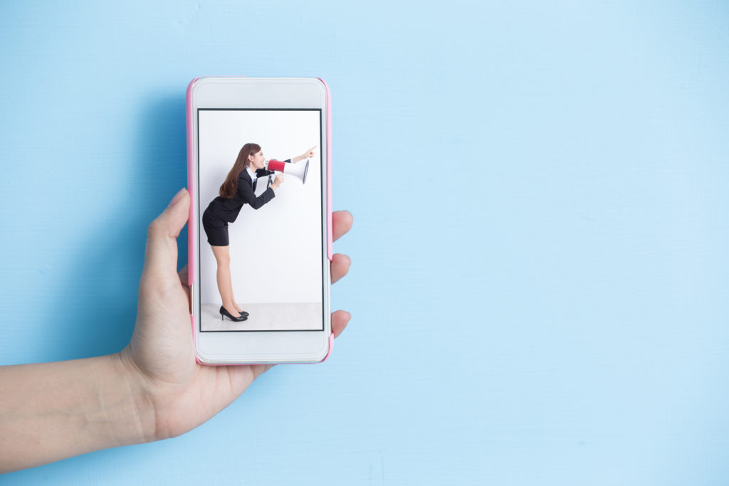 Smartphone with a picture of a woman talking through a megaphone