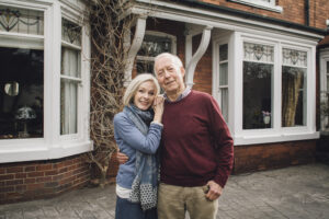 Older couple standing in front of a home smiling