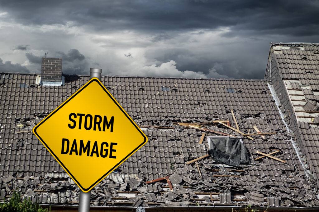 Yellow damage warning sign in front of roof of damaged house