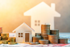 Coins stacked with house model on table