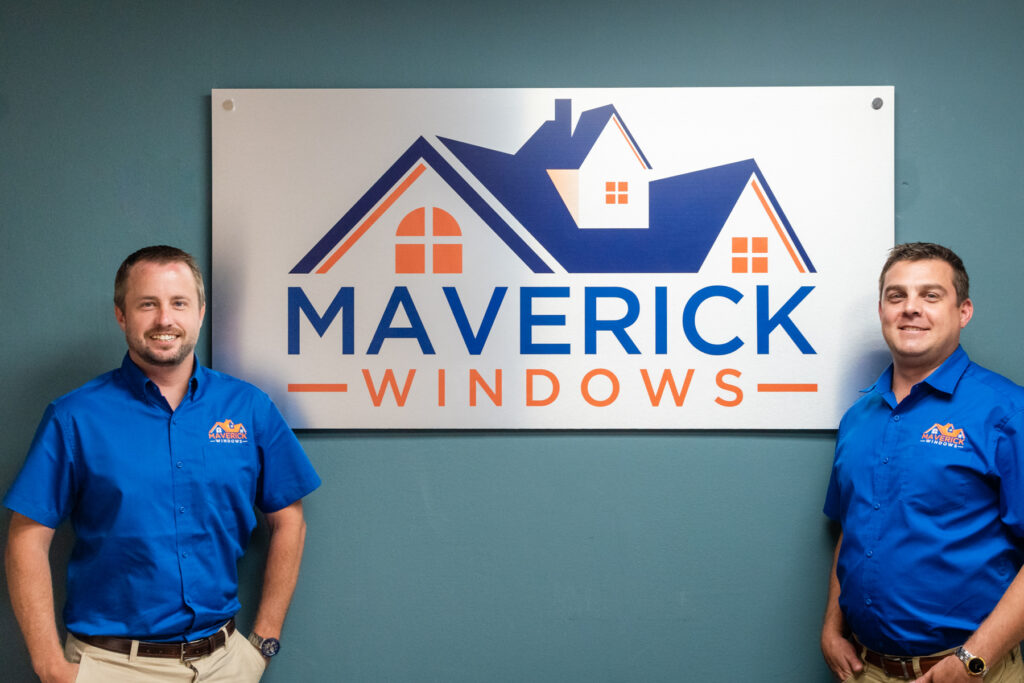 Sign hanging on the wall reading "Maverick Windows" with two businessmen smiling