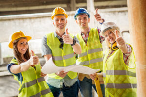 Four construction architects review plan with thumbs up