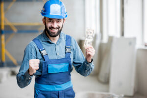 Happy construction worker standing with a handful of money