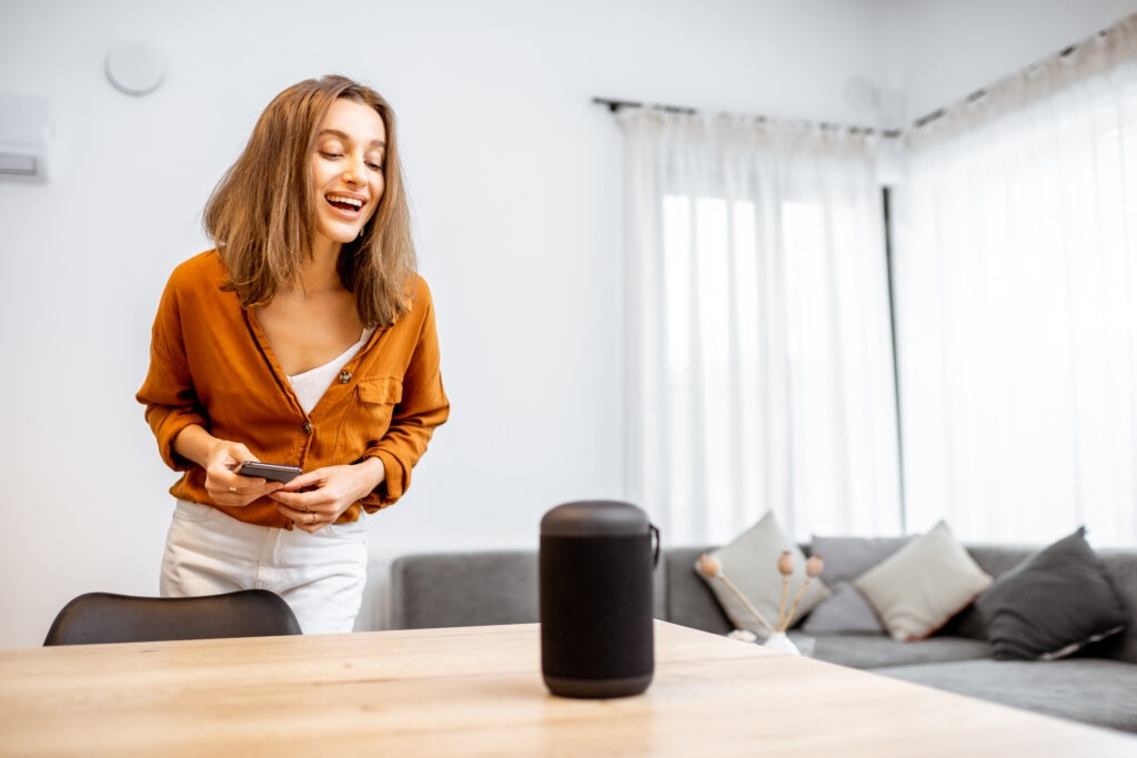 Woman controlling home devices with a voice commands and phone in hand