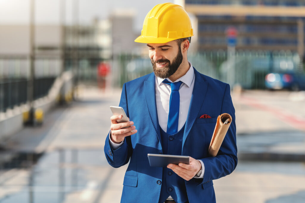 Man in formal wear using on the phone while standing on construction site