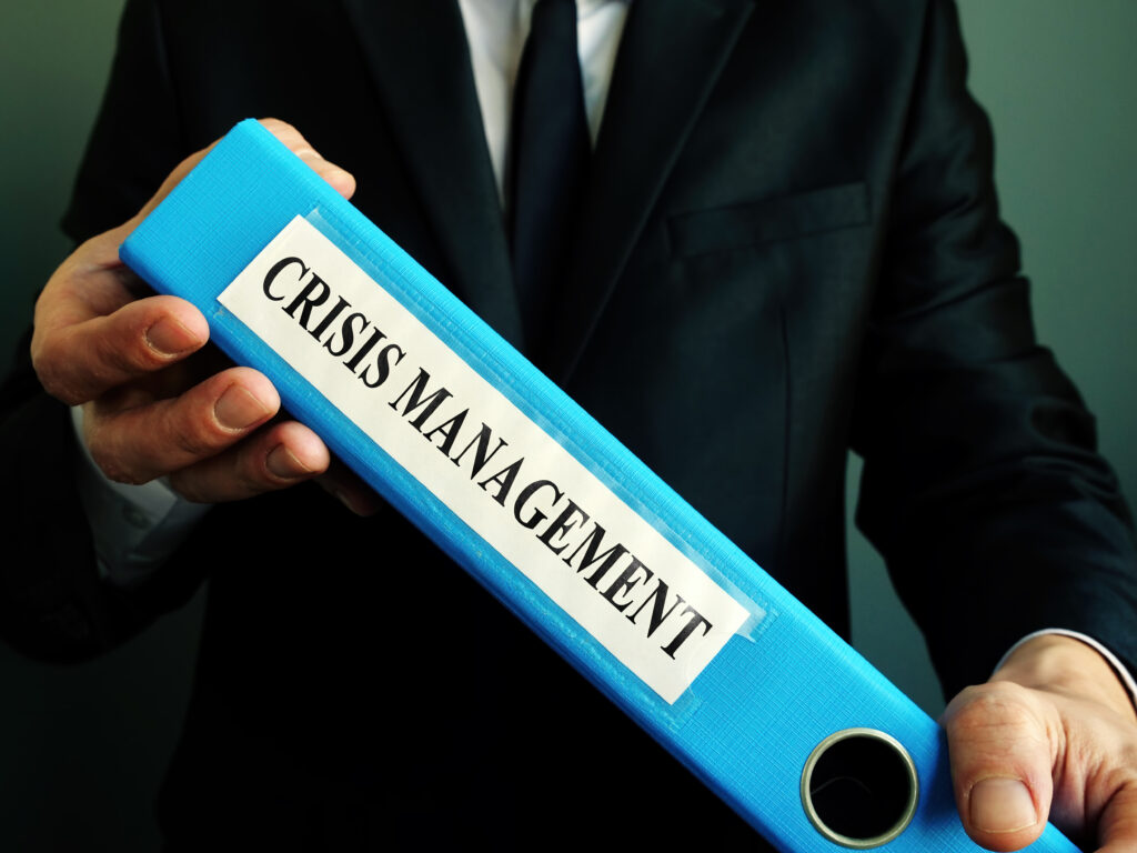 Business man holds crisis management plan in the blue binder