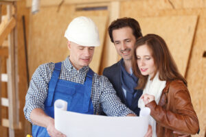 Construction worker shows design plans to a couple at construction site