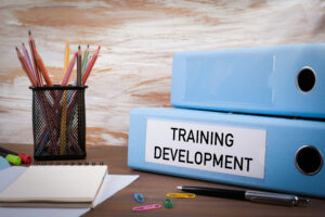 Office materials on a wooden desk with Training Development binder