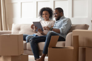 Couple using tablet on couch near stack of moving boxes