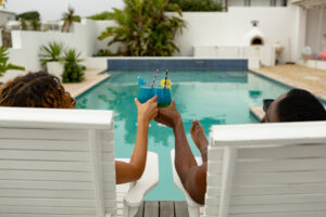 Couple toasting glasses while relaxing on a sun lounger near swimming pool