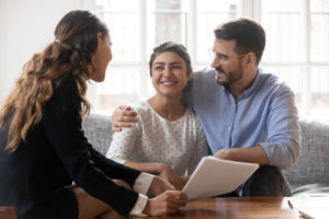 Professional female sitting across a young couple explaining contract details