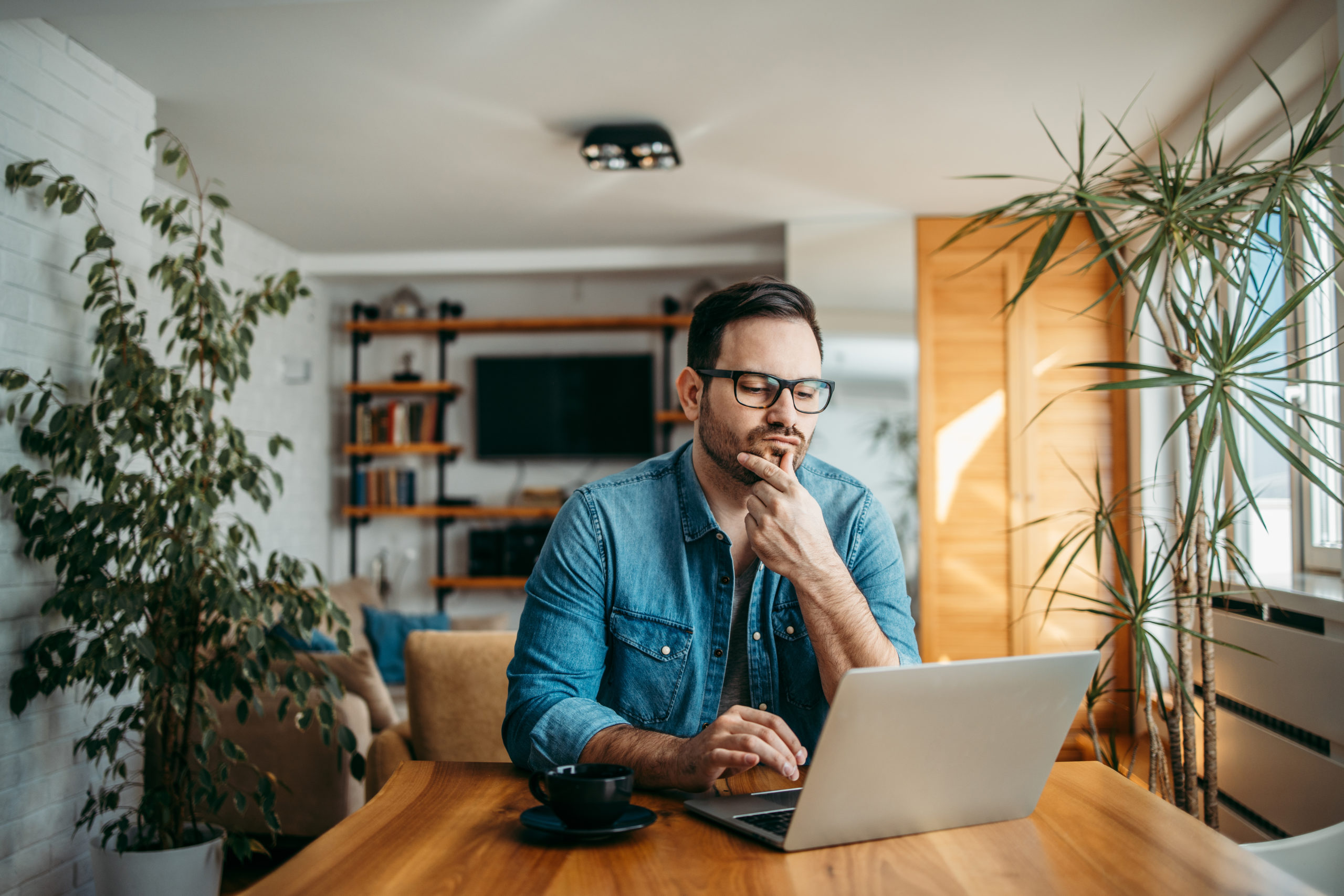 Puzzled man looking at laptop at kitchen table