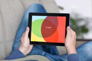 Man holding iPad with App Google on the screen