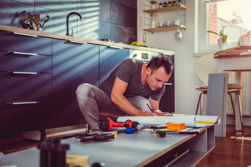 Man kneeling and working on kitchen blueprints