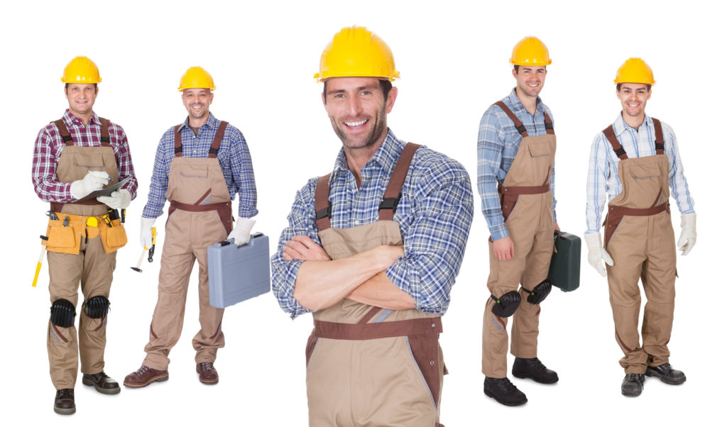 Portrait of happy construction worker standing in front of his team.