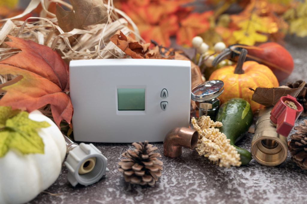 Construction tools and White thermostat with maple leaves and pumpkin. contractor thanksgiving concept. copy space.