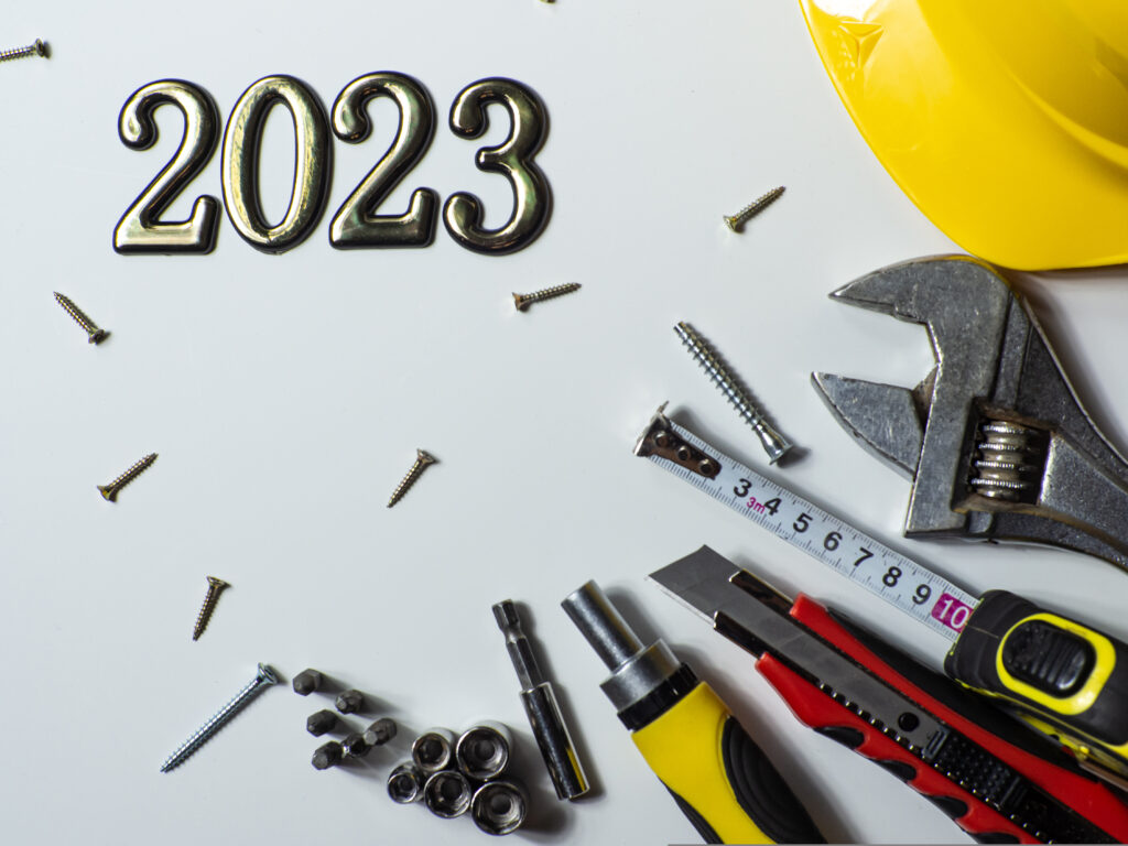 2023 business goals with tools on a table, 2023 with construction tools, yellow hard hat on white background with copy space.