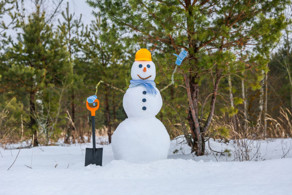 Snowman waving with shovel and construction hard hat