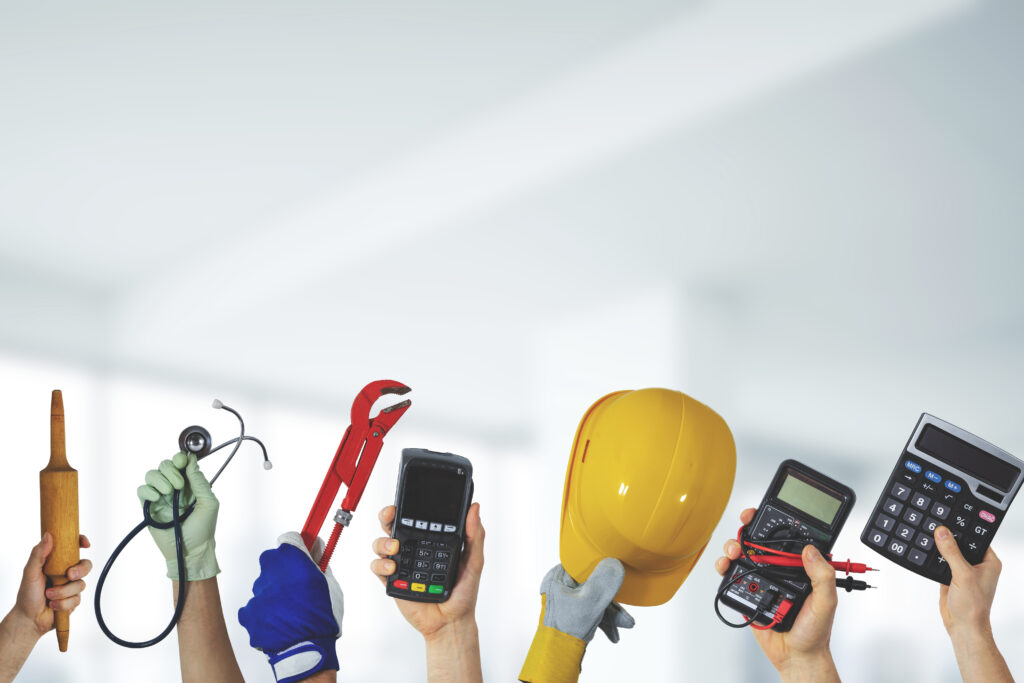 Several contractor hands holding various construction tools