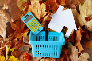 A basket with a calculator and a paper cutout of a home on top of a pile of leaves.