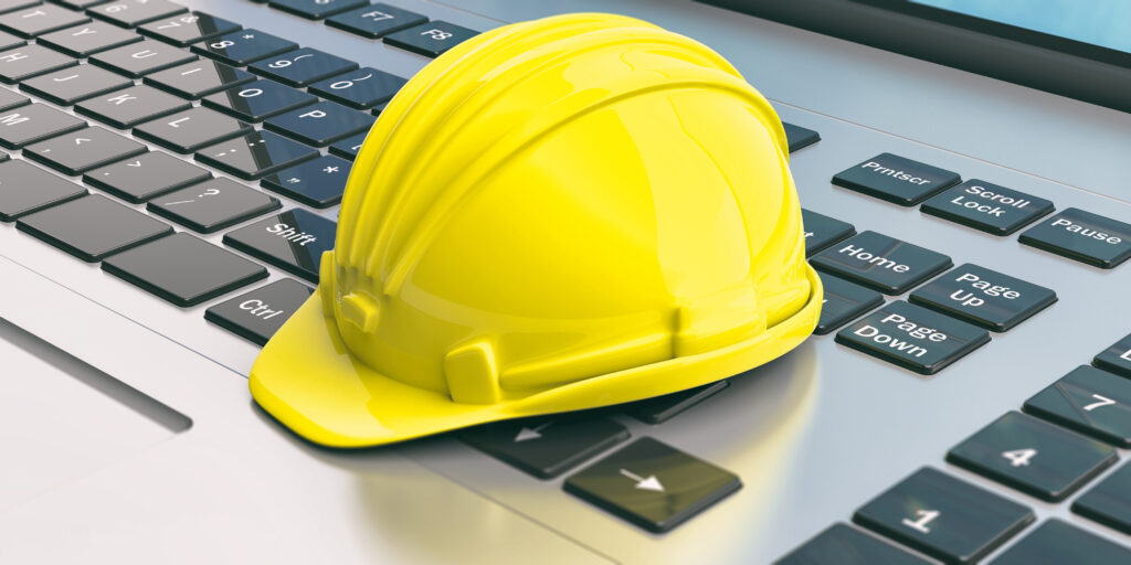 Contractor hard hat sitting on top of a laptop.