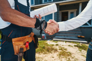 Contractor shaking hands with a homeowner in front of the house.
