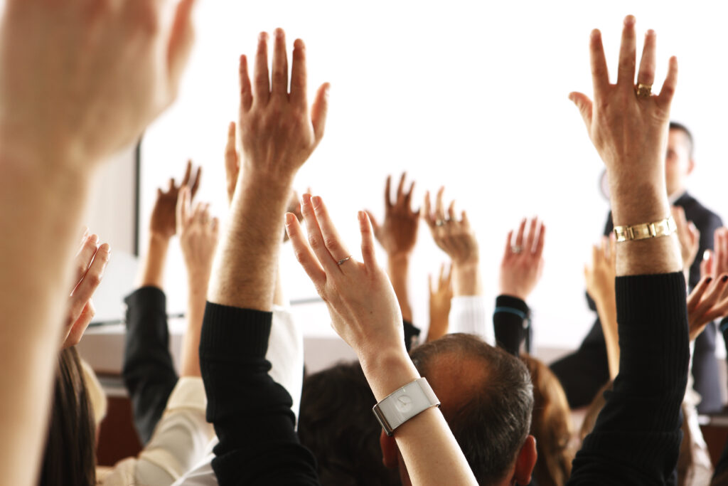 voting audience, business spectators or students raising hands in seminar