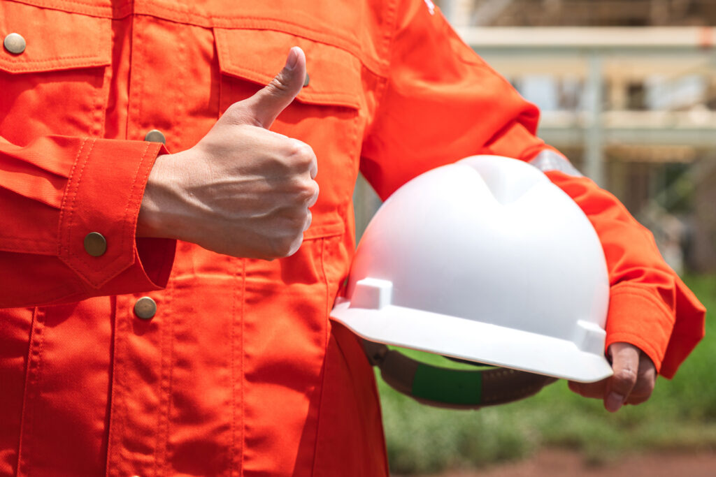 contractor holding safety helmet with refinery plant.