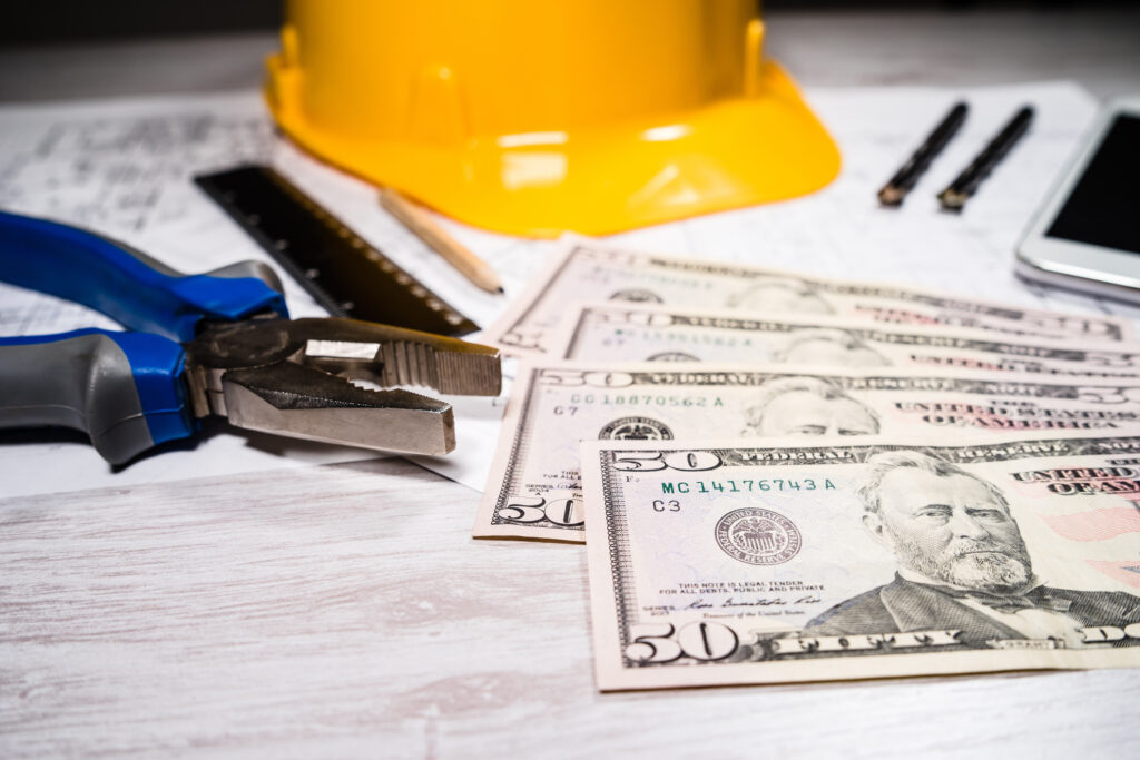 construction industry costs money us dollars banknotes by tools safety equipment and blueprints